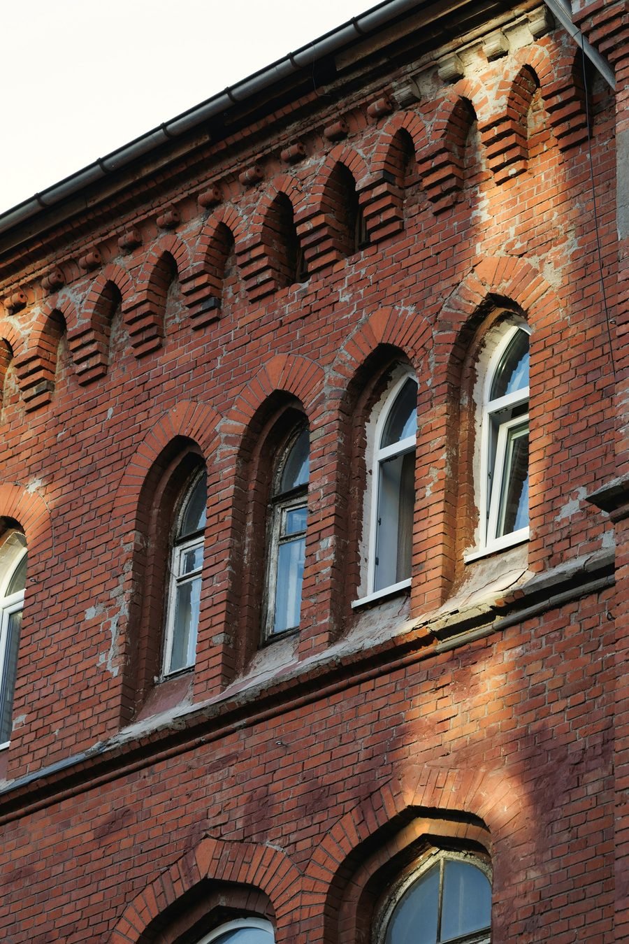 An old red brick facade with arched windows and decorative brick corbels.